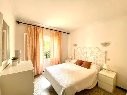 1 dormitorio con cama blanca y ventana en Montserrat I, en L'Escala