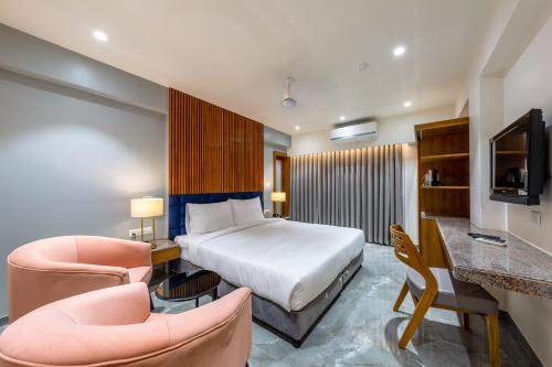 a hotel room with a bed and two chairs at Hotel Nalanda in Ahmedabad