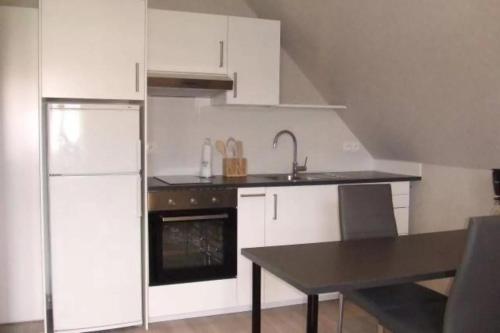 - une cuisine avec des placards blancs, un évier et une table dans l'établissement Chambre D'hotes Clos Des Pommiers, à Rosheim