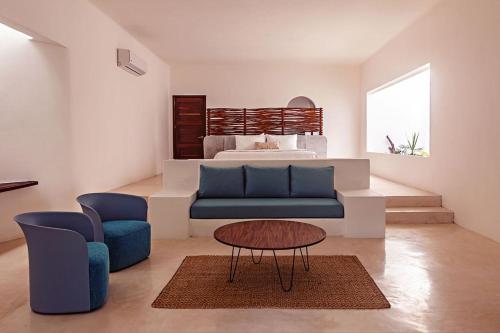a bedroom with a bed and a blue couch and a table at Mi Kasa Tu Kasa Bacalar by Nah Hotels in Bacalar