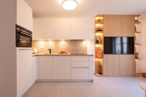 une cuisine avec des armoires blanches et un évier dans l'établissement OSCAR, appartement de standing, à Saint-Tropez