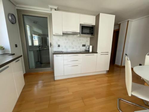 a kitchen with white cabinets and a wooden floor at Ostende Beach View apartment in Castro-Urdiales