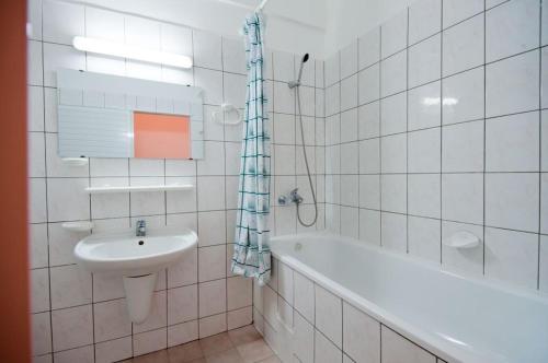 La salle de bains est pourvue de carrelage blanc, d'un lavabo et d'une baignoire. dans l'établissement Regina Hotel, à Sunny Beach