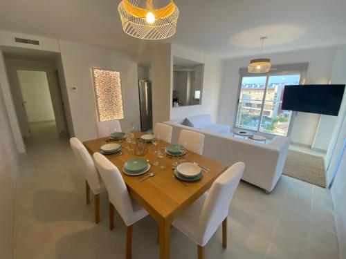 a dining room with a wooden table and white chairs at Àtico Espuma - Marenia´s Dream in Denia