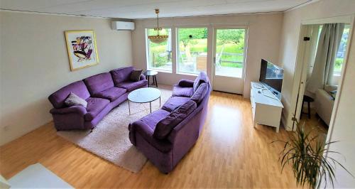uma sala de estar com sofás roxos e uma televisão em Vitahuset, 1 min Vallentuna Idrottsplats em Vallentuna