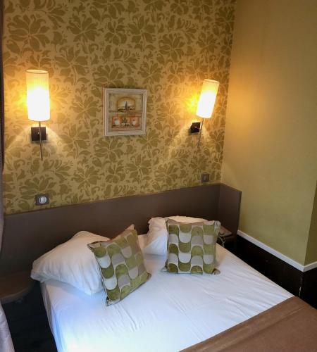 a bedroom with a bed with two pillows and two lights at Hôtel du Dauphin in Lyon