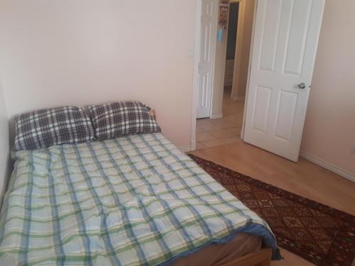 uma cama com um edredão xadrez e almofadas num quarto em W.R.M em Calgary