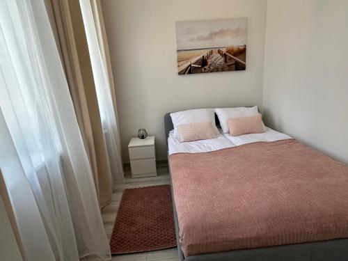 a small bedroom with a bed and a picture on the wall at Apartamenty Przy Deptaku in Świnoujście