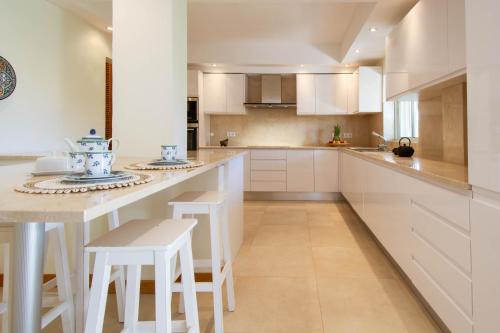 a kitchen with white cabinets and a island with stools at Casa La Vendola in Estômbar