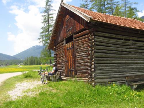 a man sitting on a bench next to a log cabin at Apartement Gute Laune in Mieming