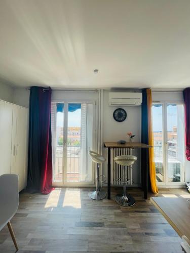 - un salon avec une table et 2 fenêtres dans l'établissement Petit Studio Centre joliette, à Marseille
