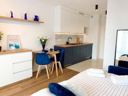 een keuken en een woonkamer met een kleine tafel en blauwe stoelen bij Healthy Life Apartment in Warschau