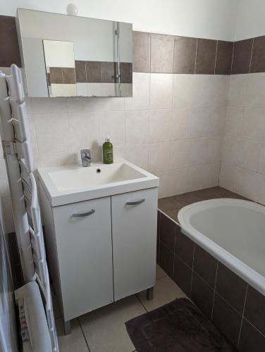 La salle de bains est pourvue d'un lavabo blanc et d'une baignoire. dans l'établissement Maison au cœur des Alpilles, à Mouriès