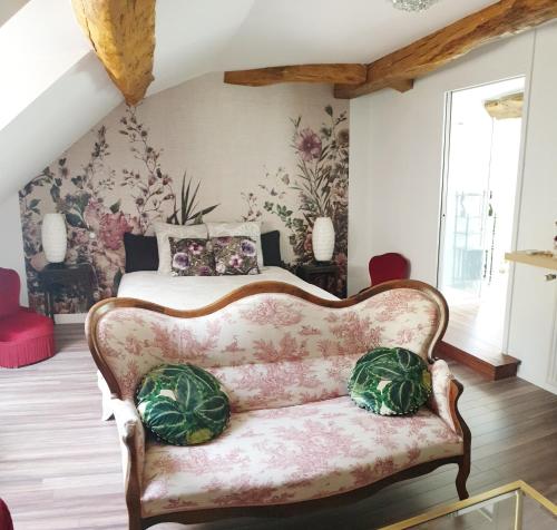 a bedroom with a bed and a couch with pillows at Maison Bélénos in Nevy-sur-Seille