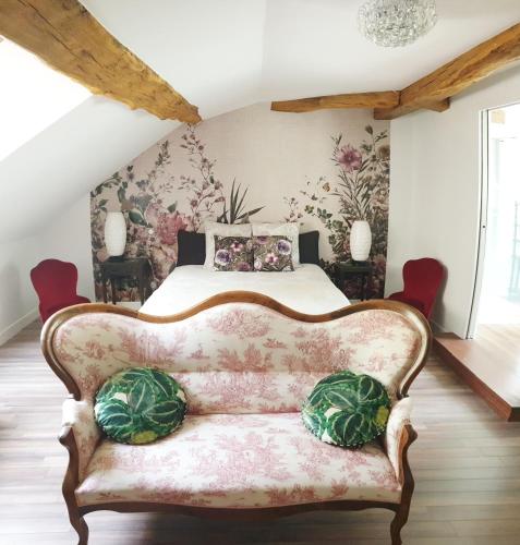 a bedroom with a bed and a couch with two pillows at Maison Bélénos in Nevy-sur-Seille