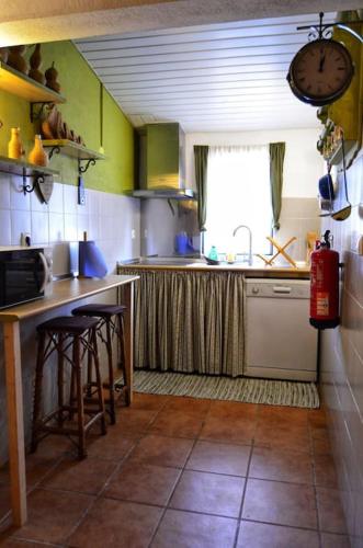 a kitchen with a counter and stools and a clock at Casa do Jardim in Montargil