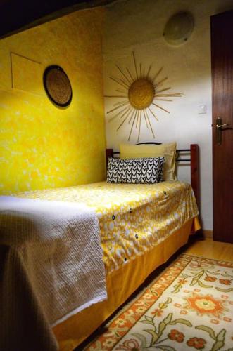 a bedroom with a yellow bed with a sun on the wall at Casa do Jardim in Montargil