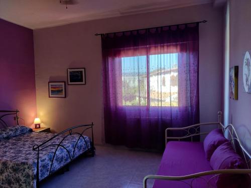 1 dormitorio con 2 camas y una ventana con cortinas moradas en Casa vacanza Sa Ferula, en Flumini di Quartu