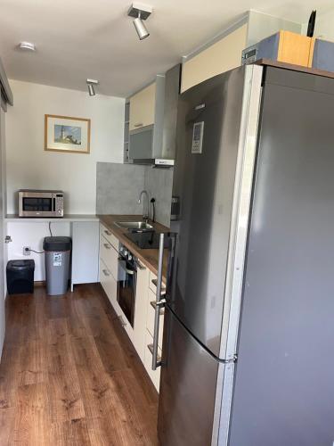 a kitchen with a stainless steel refrigerator and wooden floors at Apartmán - F - Vyhlídka nad řekou in Zdiby
