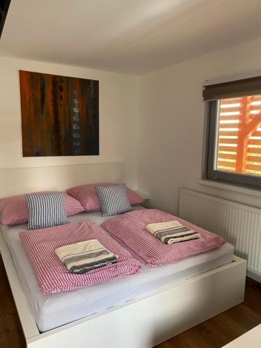 Una cama con sábanas rosas y almohadas en un dormitorio en Apartmán - F - Vyhlídka nad řekou, en Zdiby