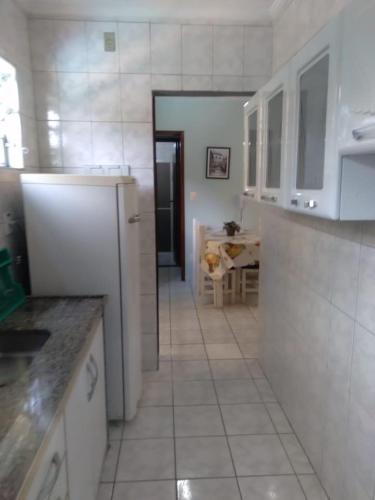 eine Küche mit einem weißen Kühlschrank und einem Tisch in der Unterkunft Apartamento com Piscina in Caraguatatuba
