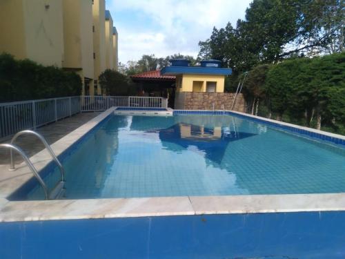 einem großen blauen Pool vor einem Gebäude in der Unterkunft Apartamento com Piscina in Caraguatatuba