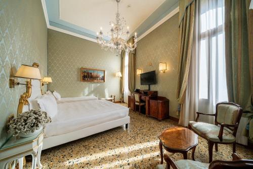 ヴェネツィアにあるホテル コロンビーナのベッドとシャンデリアが備わるホテルルームです。