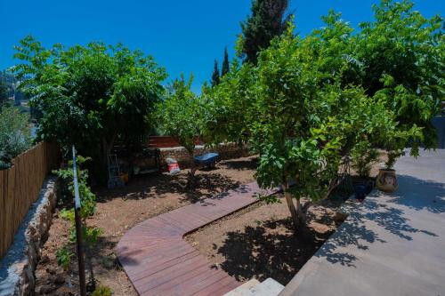 a garden with two trees and a brick walkway at פרלה צימרים in ‘En Kerem