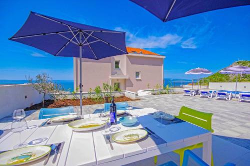 a table with chairs and an umbrella on a patio at Holiday Home Ferias in Makarska