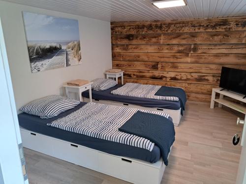 3 Betten in einem Zimmer mit Holzwänden in der Unterkunft Zimmervermietung KaSa in Groß Lafferde