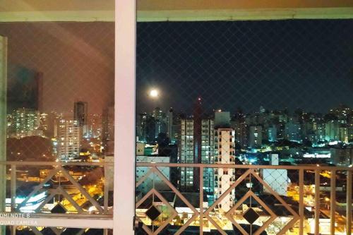 a view of a city at night from a window at Apartamento moderno com 03 quartos e 02 garagens in Campinas