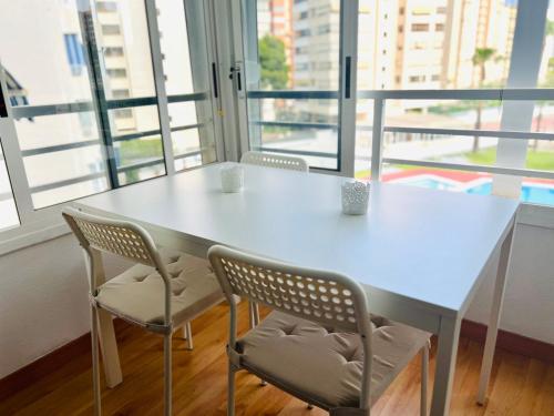 アリカンテにあるPlaya Dos Avenidasの窓付きの客室で、白いテーブルと椅子が備わります。