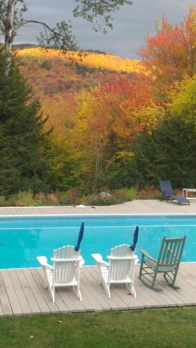 two chairs sitting next to a swimming pool at Cricket Hill Lodging in Killington