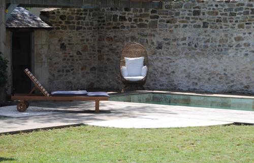 a wicker chair and a chair next to a pool at Maison Balmelle - Maison d'hôtes de Caractère in Gramat