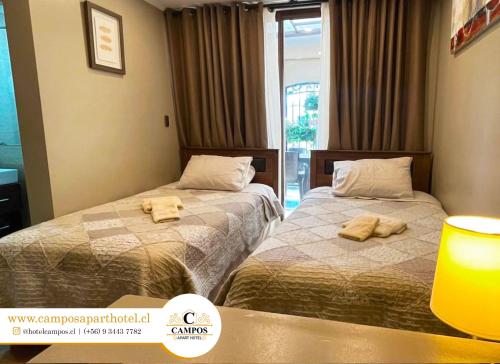 Dos camas en una habitación de hotel con toallas. en Apart Hotel Campos Rancagua, en Rancagua