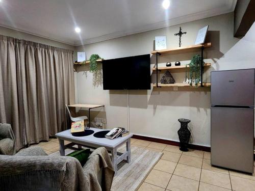 a living room with a couch and a tv at Lily Rest Garden Cottage in Pretoria