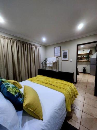 a bedroom with two beds and a yellow blanket at Lily Rest Garden Cottage in Pretoria