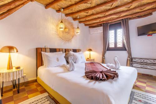 una camera da letto con un letto con due cigni sopra di Dar Khmissa Riad & Spa a Marrakech