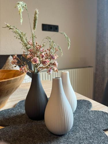 three white vases sitting on a table with flowers at Ferienwohnung Florina im Hotel Casada in Galtür