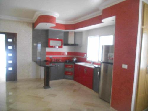 a kitchen with red walls and stainless steel appliances at Route de la plage in Kelibia