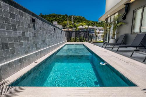 uma piscina com água azul numa casa em Top Studios Canasvieiras TPS em Florianópolis
