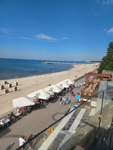 una spiaggia con ombrelloni e persone sedute sulla spiaggia di Kołobrzeg Apartamenty Monada, Towarowa 50m od morza a Kołobrzeg