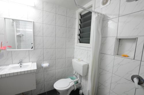 a white bathroom with a toilet and a sink at Talofa Inn in Apia