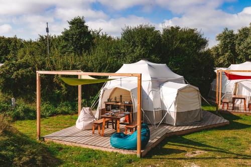 a tent with a table and chairs in a field at DOMO CAMP Sylt - Glamping Camp in Westerwall