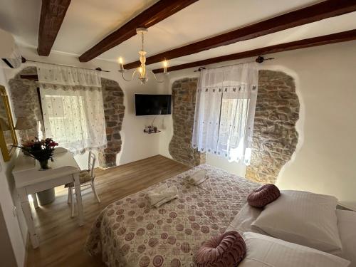 um quarto com uma cama, uma mesa e janelas em Casa Stella em Draguć
