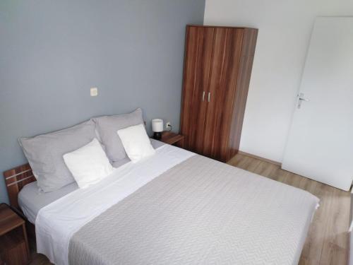 a bedroom with a large bed with white sheets and wooden floors at Apartment Lil in Podstrana