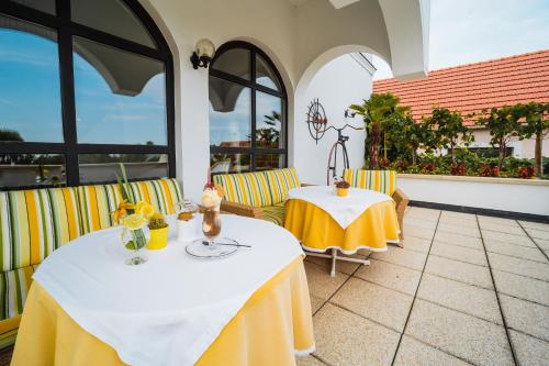 a patio with two tables and chairs and windows at Das-Schmidt Privathotel in Mörbisch am See