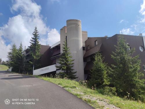 a building on the side of a road with trees at Beau studio cabine cozy in Chamrousse