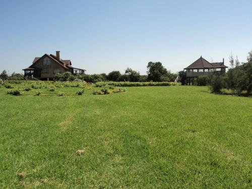 a field of grass with two houses in the background at Sangare Gardens- Book Now Enjoy Free Farm Tour in Mweiga
