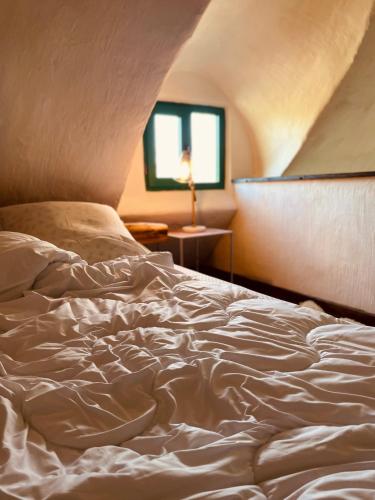 an unmade bed in a room with a window at Inside, The Village- Atelier in Tunari